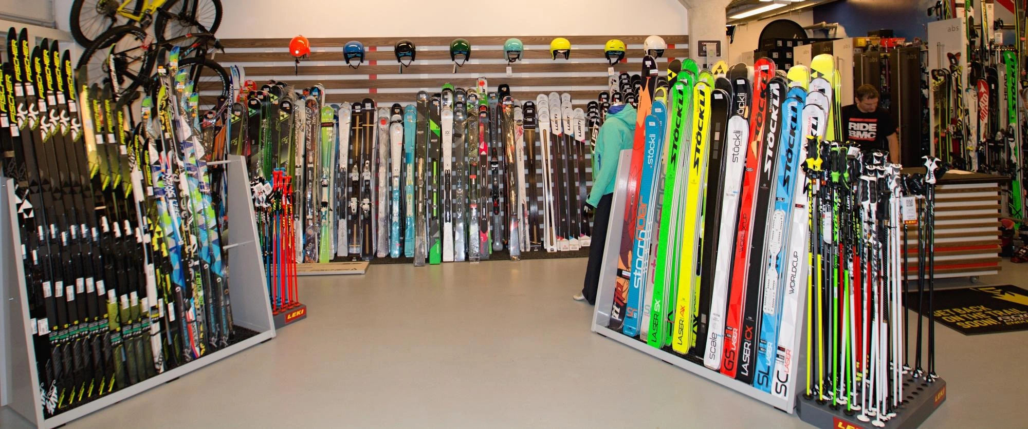 Colorful skis, ski poles, and helmets displayed for sale inside a winter sports retail store.