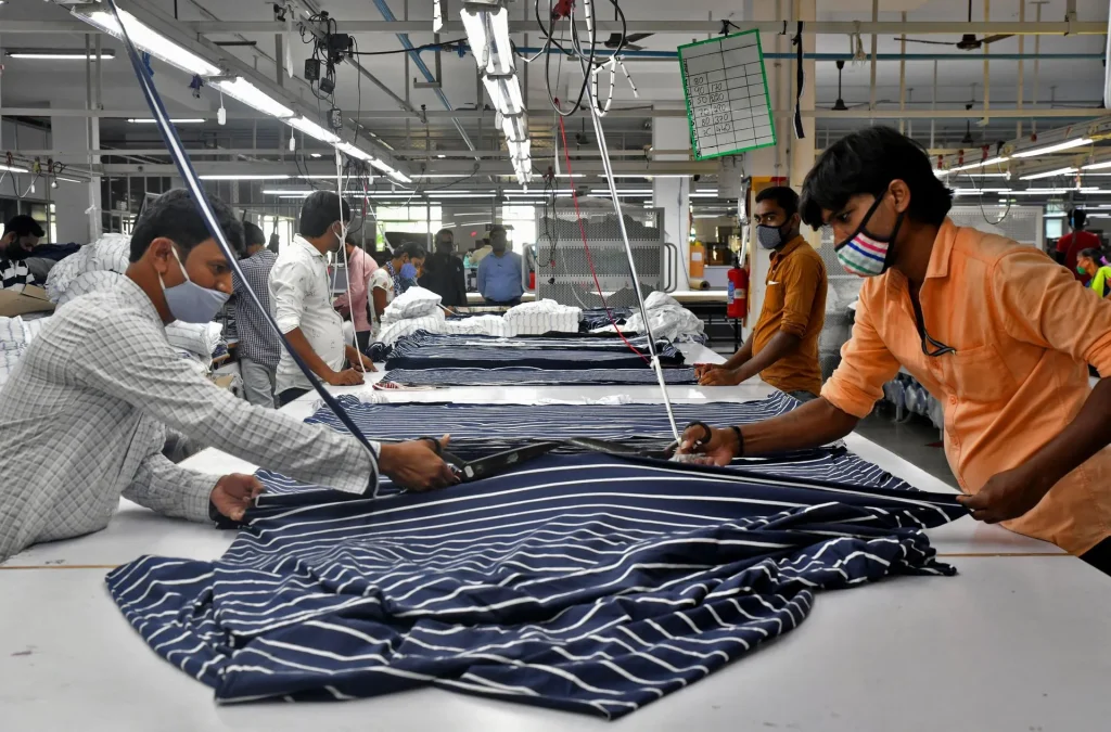 Skilled workers using professional shears to cut striped fabric at a textile manufacturing facility.