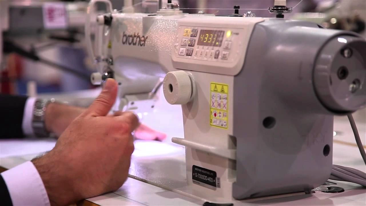 Close-up of a Brother S-7000DD-403 industrial sewing machine in operation at a garment manufacturing facility