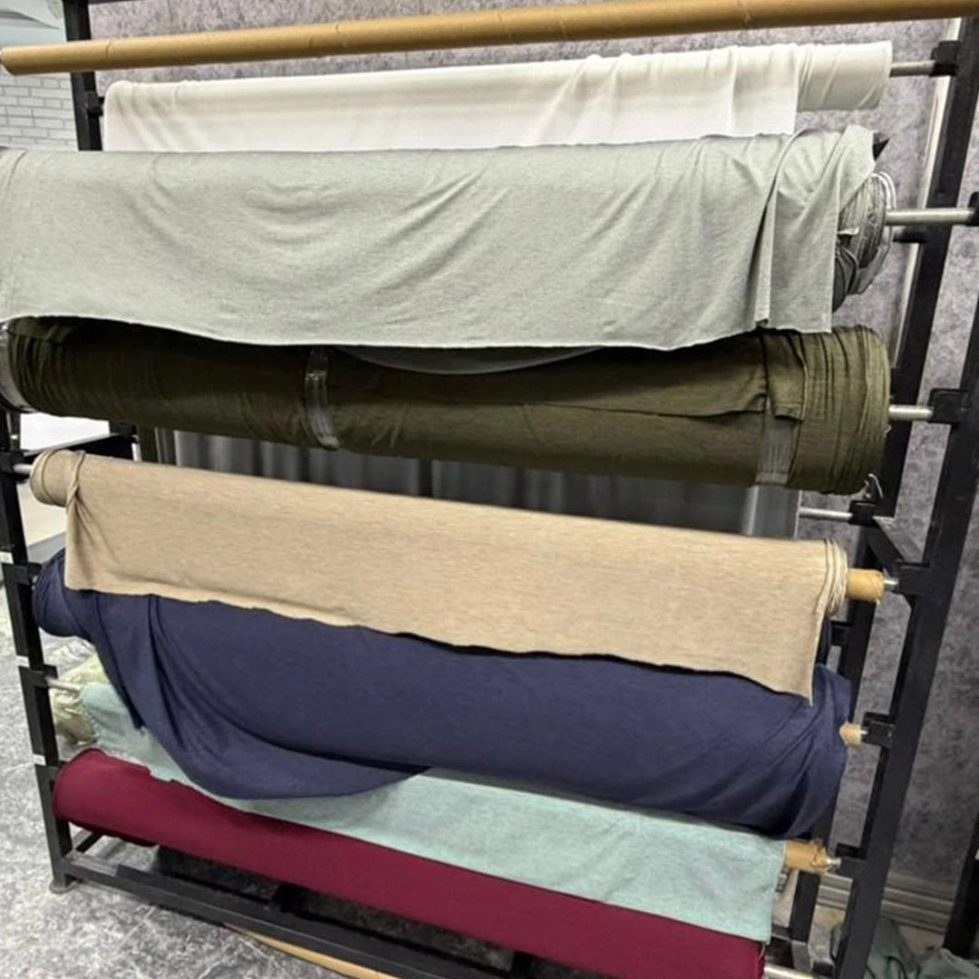 A variety of fabric rolls in different colors stacked on a professional industrial storage rack for garment manufacturing.